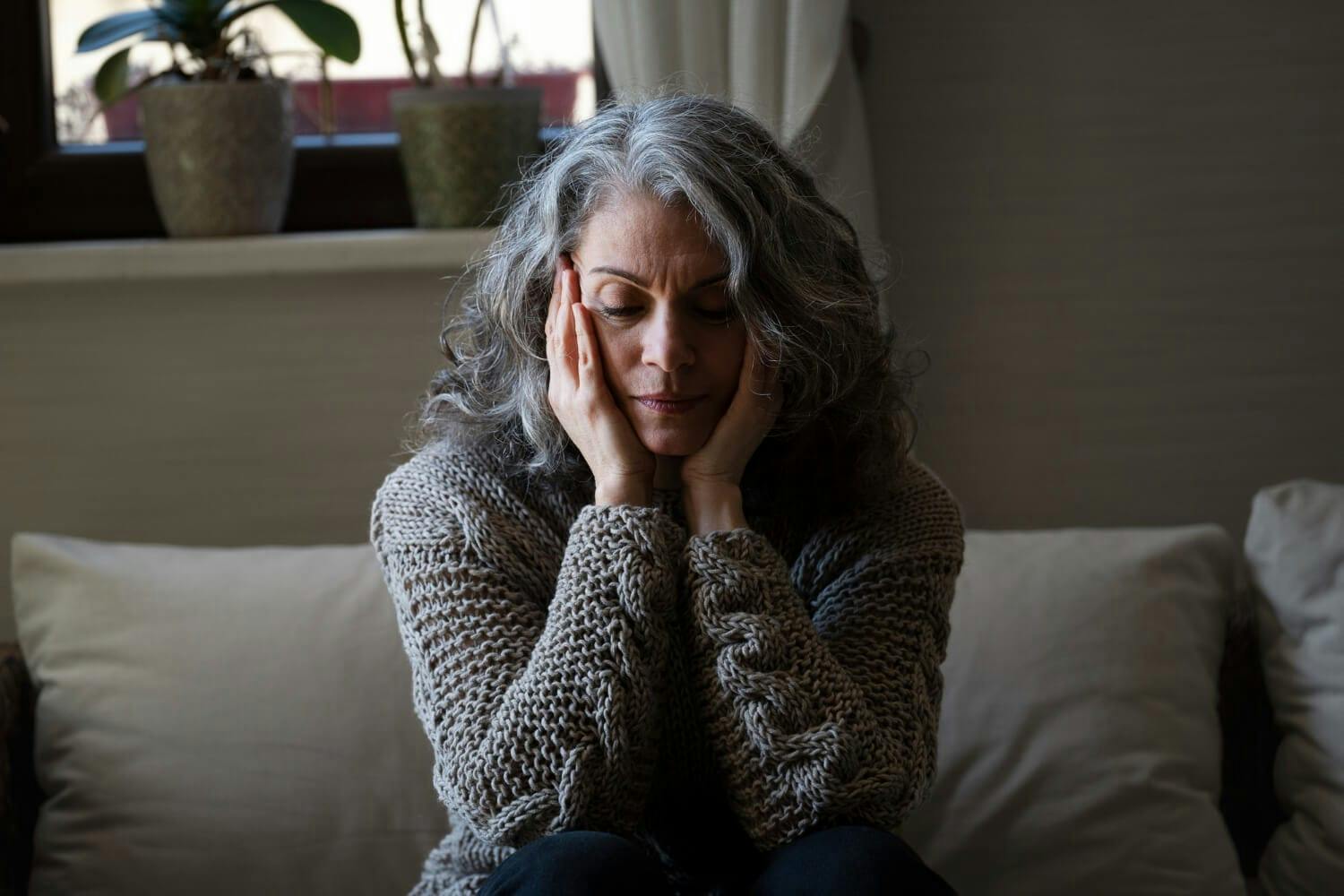 chronic stress - a lady with a gray hair placing her hand on head due to stress