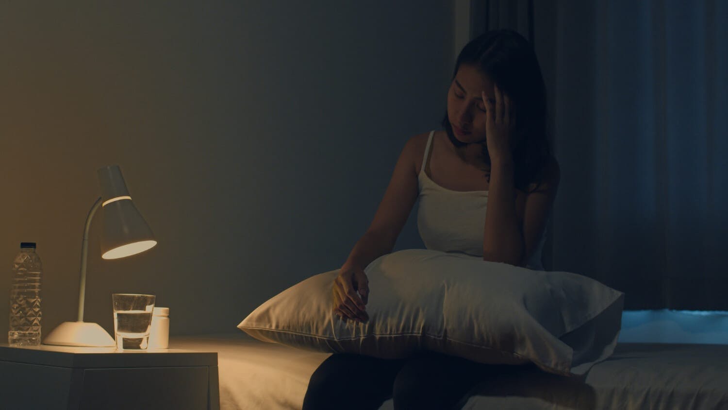 young woman sitting on bed - poor sleep due to depression