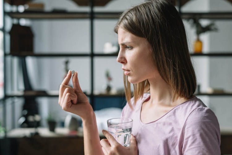 Side view of a sick young woman looking at SNRI pill