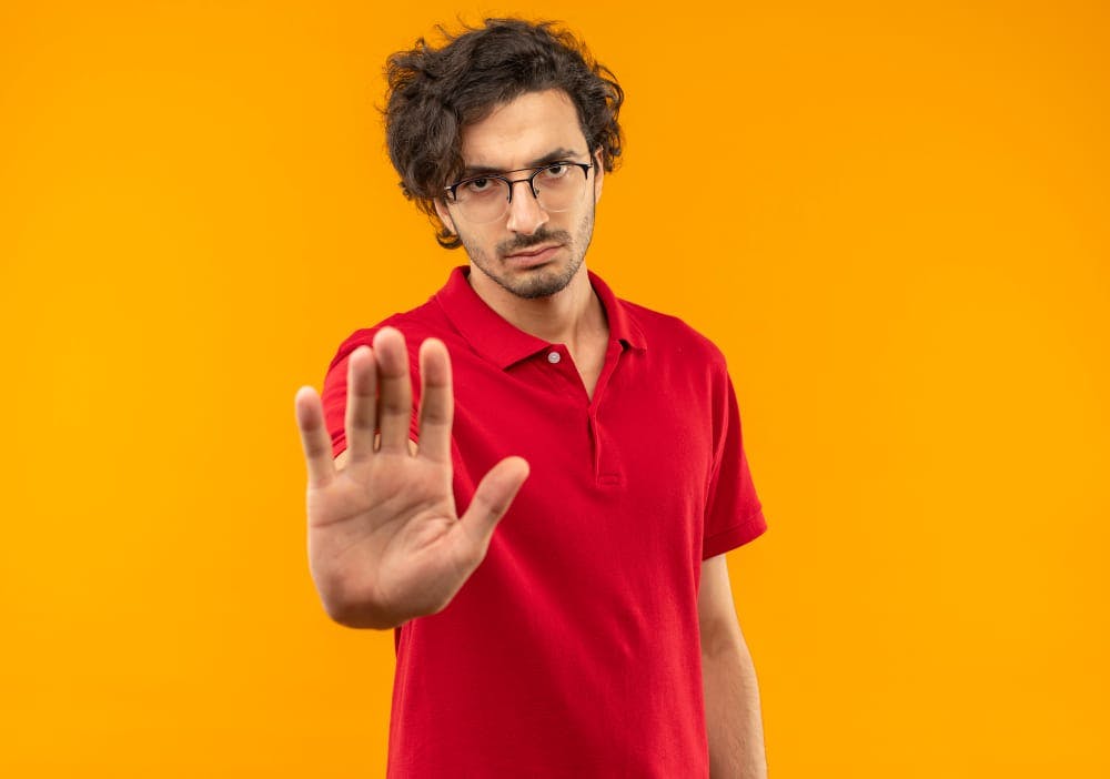 man in red shirt showing hand sign like stop not to tell anything to your therapist