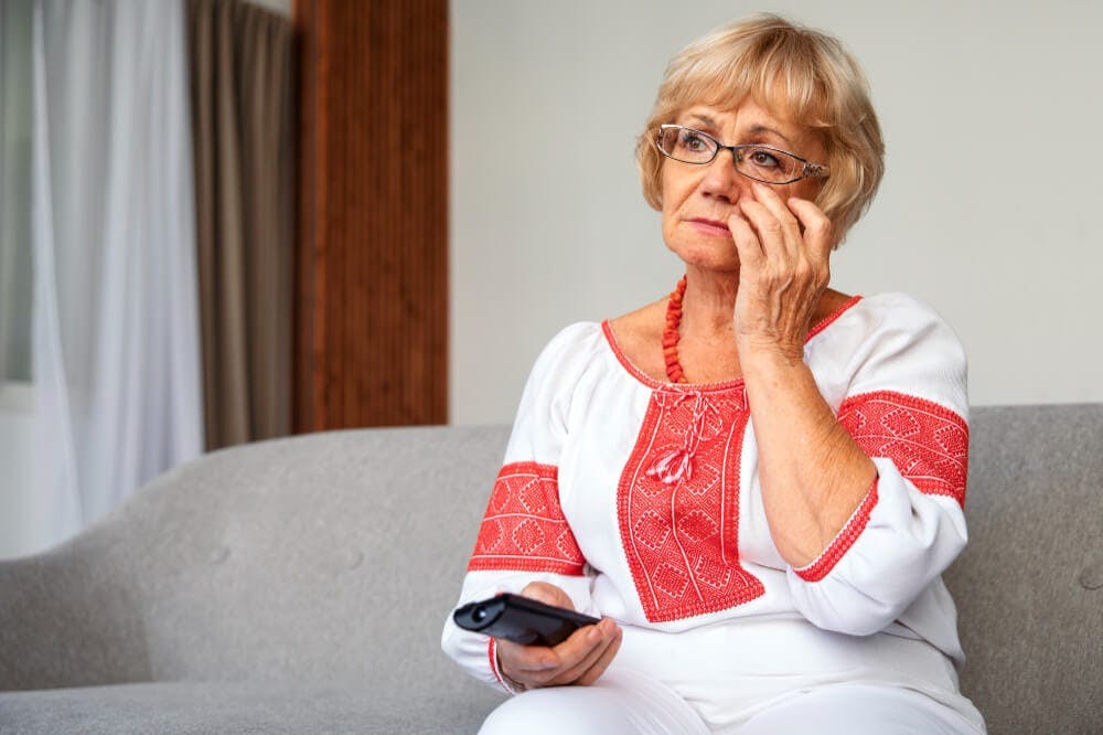 old aged mom watching news on tv - stay at home mom