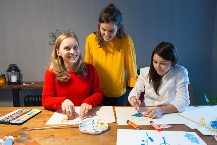 Cheerful art therapy teacher and students enjoying painting class for Mental health Benefits 