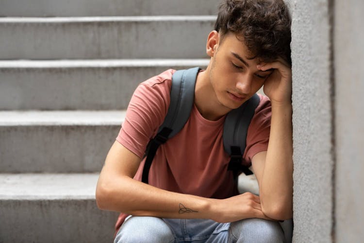 Sad and depressed young Indian boy sitting on stairs 