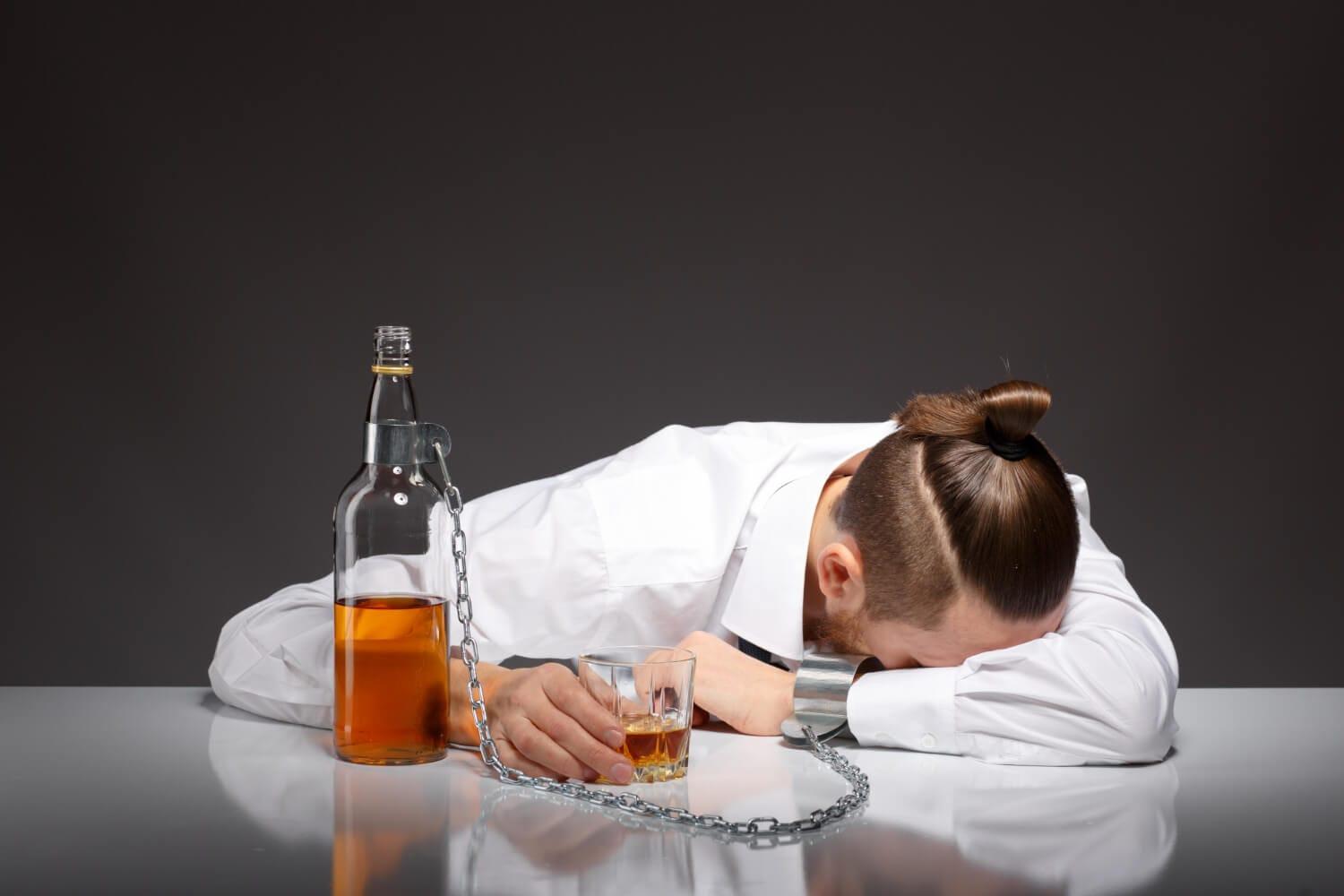 Tired young businessman drinking and suffering from mental health issue