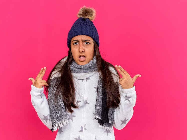 girl wearing winter hat with scarf points at herself isolated on pink background-Fight, Flight, Freeze, Fawn