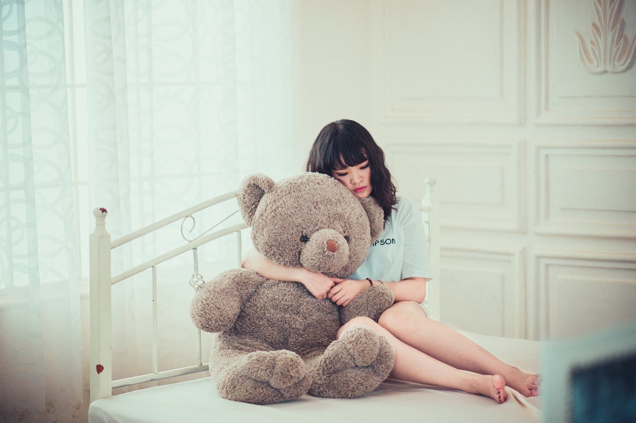 A young girl with teddy with a sad facing thinking - Why Am I Sad for No Reason? Do I have Mental Health Issues?