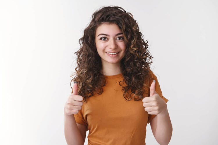 happy impressed attractive supportive girl wearing orange tshirt show thumbsup approval and acceptance and commitment