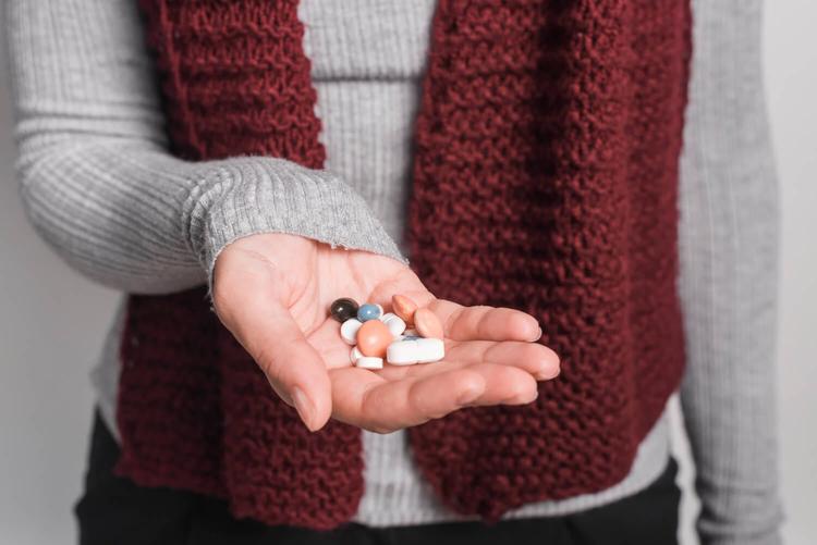 Close-up of woman holding many pills in hand 