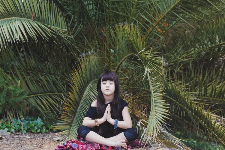 Girl meditating under palm to optimize her brain with various therapy like meditation techniques